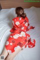 A woman in a red kimono laying on a bed.