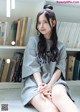 A woman sitting on the floor in front of a bookshelf.