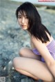 A woman in a purple bathing suit sitting on the beach.