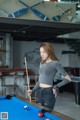 A woman standing next to a pool table holding a cue.