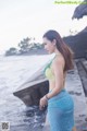 A woman in a blue and green bikini standing by the water.