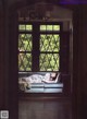 A woman laying on a couch in front of a window.