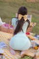 A woman sitting on a picnic blanket with a basket of food.