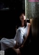 A woman in a white dress sitting by a window.