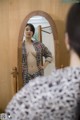 A woman standing in front of a mirror in a room.