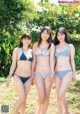 A group of three women in bikinis standing next to each other.